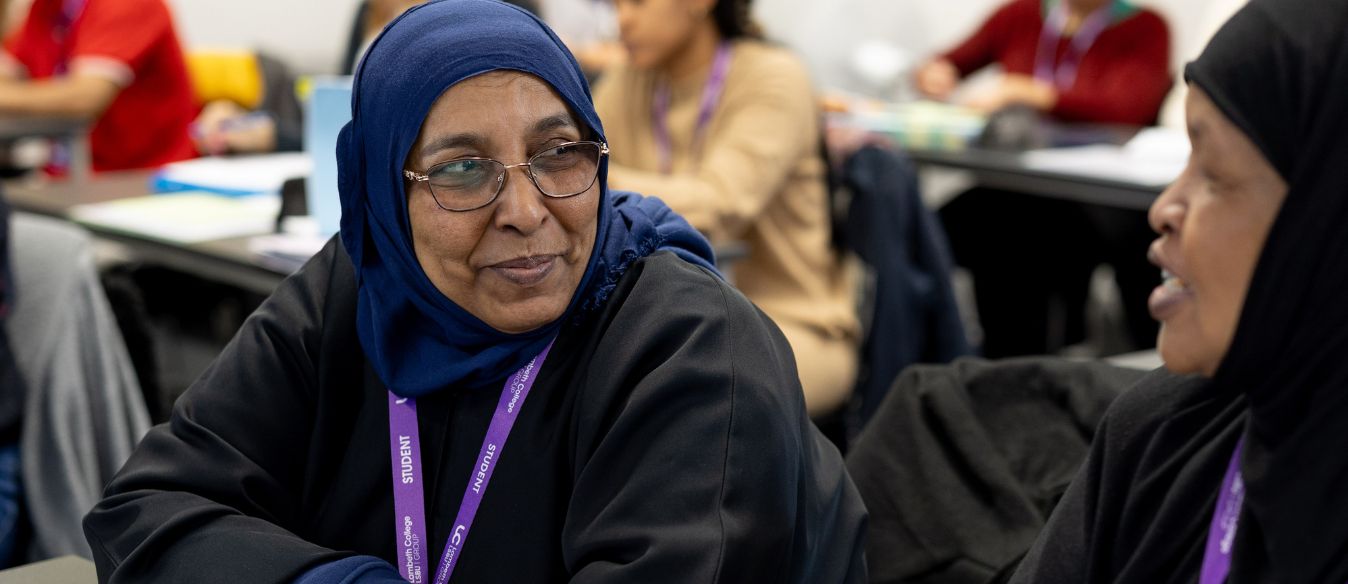 One Lambeth College student and one staff lecturer, posing and smiling to each other