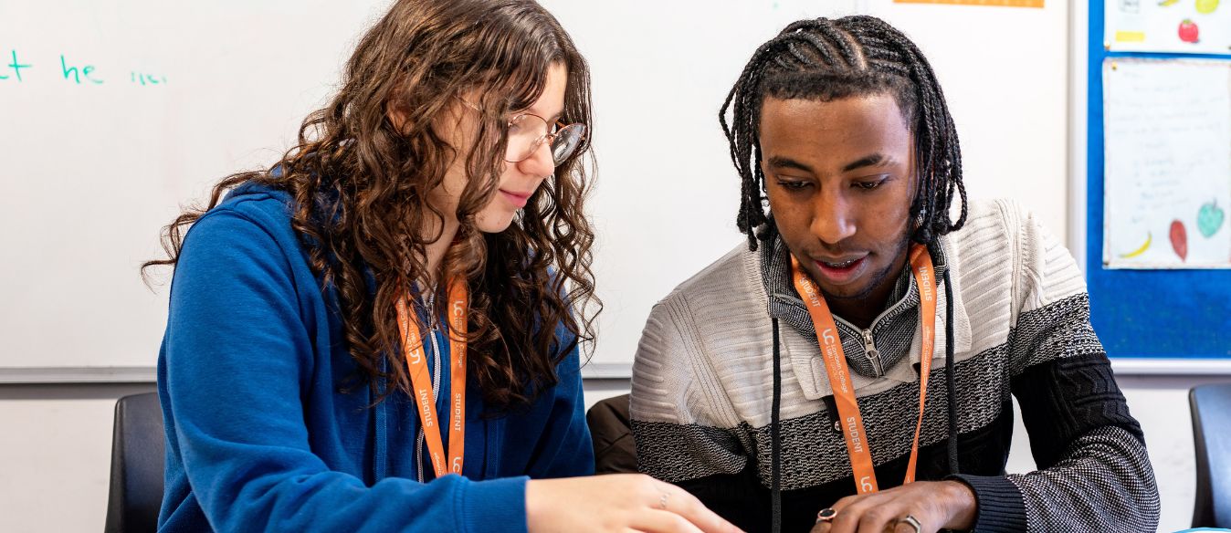 Two Lambeth College students, examining a map, engaged in conversation as they identify various places on the map.